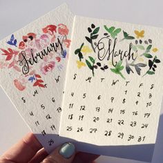 two handmade calendars are held up in front of a white background with colorful flowers