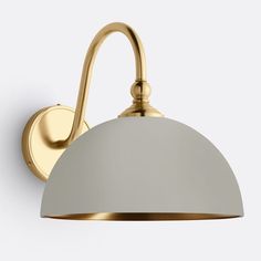 a white and gold wall light with a curved shade on the top of it's arm