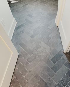 an empty bathroom with gray tile flooring and white trim on the door way to the toilet