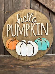 a wooden sign that says hello pumpkin with three small pumpkins in front of it