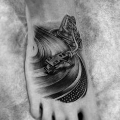 a person's foot with a tattoo on it and a record player in the background