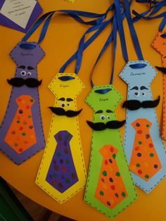 some paper ties are on a table with tags attached to the neckties that have faces and mustaches