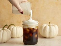 a person is pouring something into a jar filled with liquid and pumpkins in the background