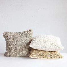 three pillows stacked on top of each other in front of a white wall and floor