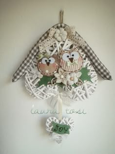 two owls sitting on top of a white birdhouse with green leaves and flowers hanging from it's side