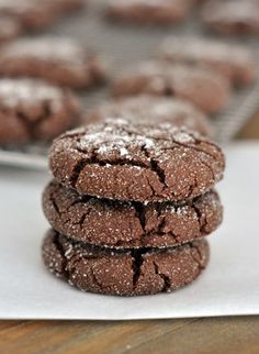 three chocolate cookies stacked on top of each other with powdered sugar in the middle