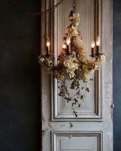 a chandelier with flowers hanging from it's sides in front of a door