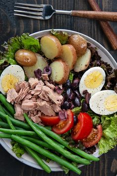 a white plate topped with meat and veggies on top of a wooden table