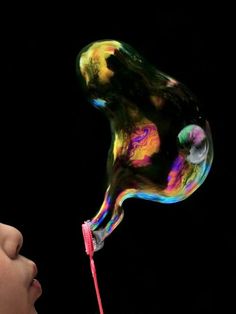 a young child is blowing soap on a toothbrush with colorful liquid pouring out of it