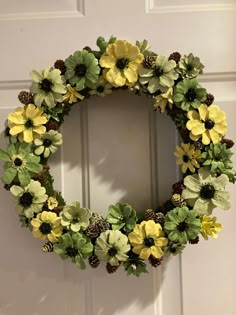 a wreath with yellow and green flowers hanging on the front door to decorate it for christmas