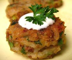 some food is sitting on a plate with white sauce and green garnishes