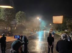 people are standing on the street at night with their camera equipment in front of them