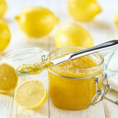 a jar filled with lemon curd next to sliced lemons