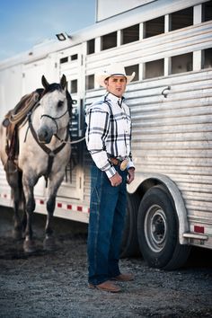 a man standing in front of a horse trailer