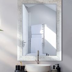 a bathroom sink sitting under a mirror in front of a white wall mounted faucet