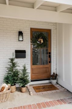 the front door is decorated with wreaths and potted trees