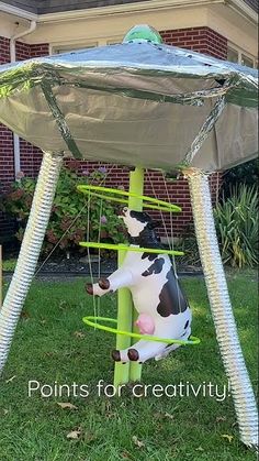 a cow in a swing made out of tin foil