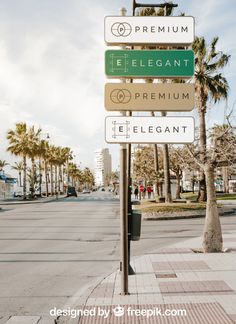 a street sign on the side of a road with palm trees and buildings in the background