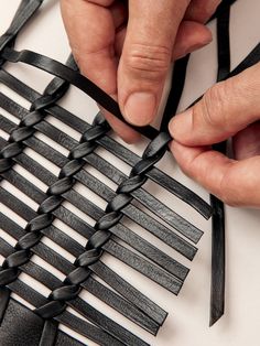 a person is cutting leather strips with scissors