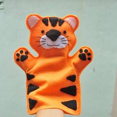 a hand is holding up a small stuffed animal that looks like a tiger's paw