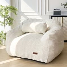 a large white chair with two pillows on it's back in a living room