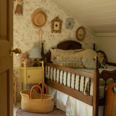 a bed room with a neatly made bed next to a basket and pillows on the floor