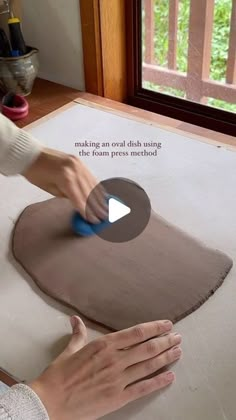 a person is using a sponge to make an oval dish using clay