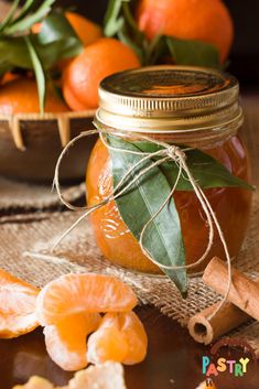 a jar filled with oranges sitting on top of a table next to sliced oranges