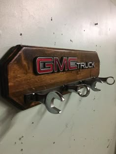 the gmc truck logo is mounted on a wall with two pairs of wrenches