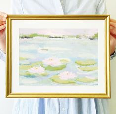 a person holding up a painting with water lillies