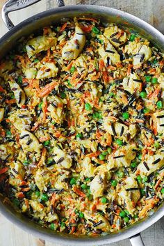 a pan filled with rice and vegetables on top of a wooden table