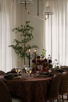 a dining room table is set with wine glasses and place settings for two people to sit at