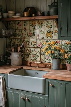 a kitchen with green cabinets and yellow flowers on the counter top, next to a sink