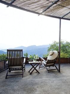 two chairs and a table on a patio with mountains in the backgroung