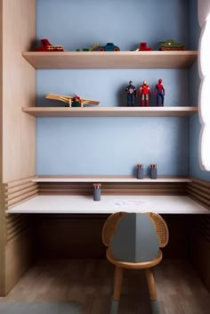 a desk with toy cars on top of it in a room that has blue walls and wooden shelves