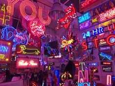 many neon signs are hanging from the ceiling in this room filled with lights and decorations