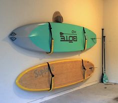 two surfboards mounted to the side of a wall next to paddles and poles