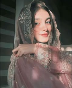 a woman wearing a veil and dress posing for the camera