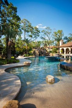 an outdoor swimming pool surrounded by palm trees and water features rock steps leading up to the waterfall