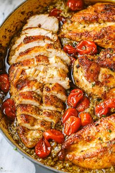 a pan filled with chicken and tomatoes on top of a table