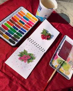 a table topped with lots of different colored paints and paintbrushes next to a cup of coffee