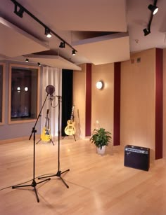 an empty room with guitars and microphones on the floor in front of a window