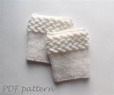 two white knitted mittens sitting next to each other on top of a table