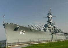 a large battleship sitting on top of a lush green field