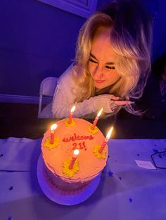 a woman blowing out candles on a birthday cake with the words happy birthday written on it