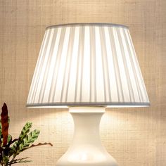 a white lamp sitting on top of a table next to a potted plant