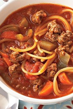 a white bowl filled with meat and vegetable soup on top of a blue table cloth