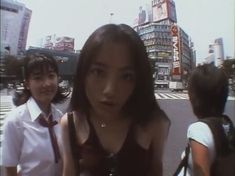 two girls are standing in the street and one is looking at the camera while the other looks on