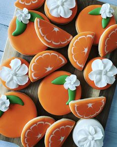 decorated cookies with oranges and white frosting on a cutting board