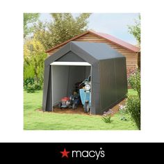 an image of a storage shed with lawn mowers in the back ground and trees behind it